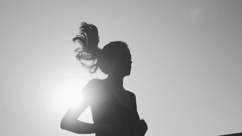  a young woman jogging in front of the sun 